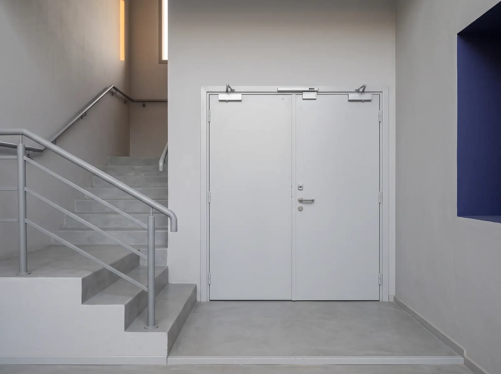 Porte coupe-feu métallique deux vantaux fermée sur le palier d'une cage d'escalier